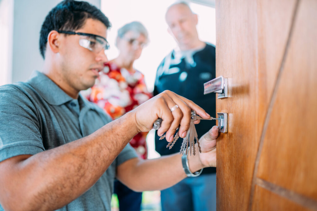 Close-up of male hands repair or installing a metal door lock. Senior couple in the background.